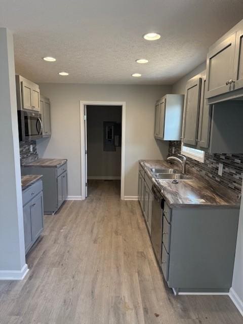 kitchen with gray cabinetry, sink, stainless steel appliances, decorative backsplash, and light wood-type flooring