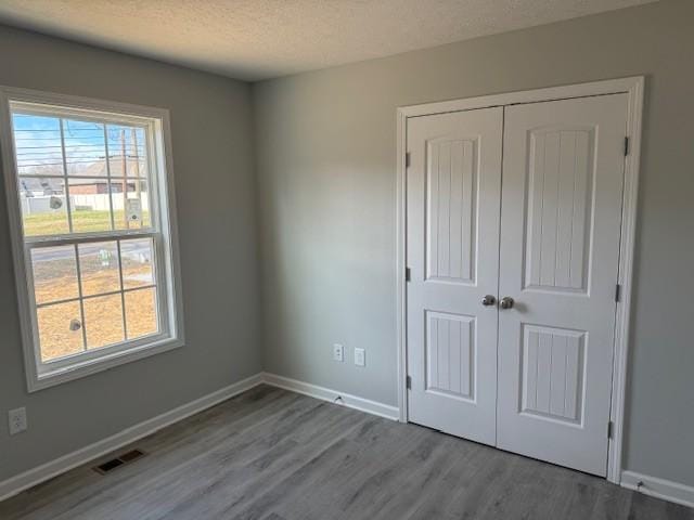 unfurnished bedroom with a textured ceiling, light wood-type flooring, and a closet