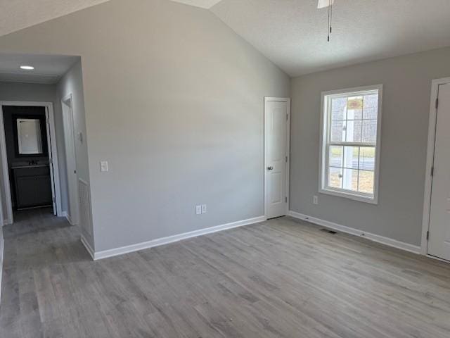 unfurnished room featuring light wood-type flooring and vaulted ceiling