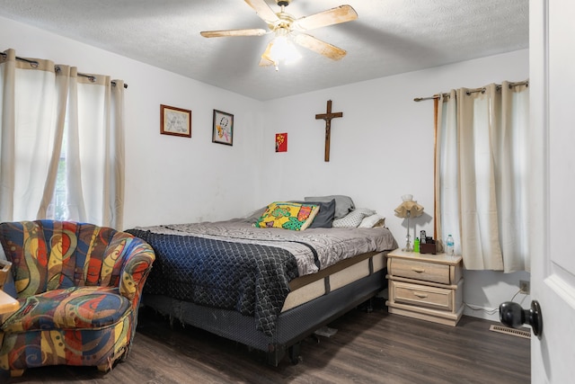 bedroom with ceiling fan, a textured ceiling, and dark hardwood / wood-style floors