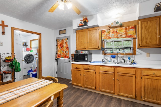 kitchen with ceiling fan, sink, washing machine and clothes dryer, a textured ceiling, and dark hardwood / wood-style flooring