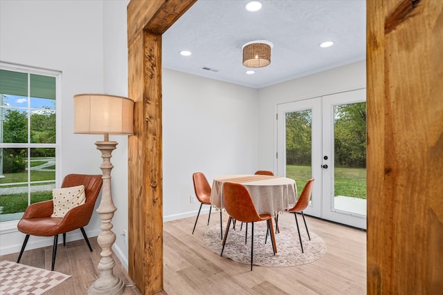 dining space with a textured ceiling, light hardwood / wood-style floors, and french doors