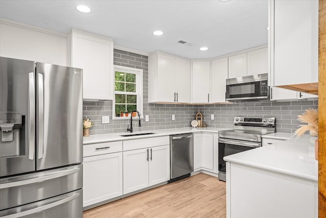 kitchen featuring light hardwood / wood-style flooring, appliances with stainless steel finishes, sink, and white cabinetry