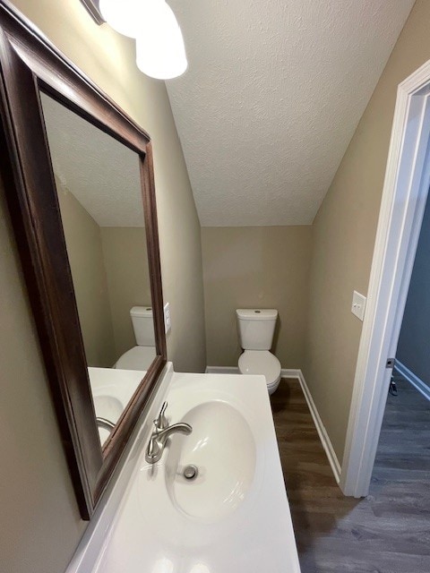 bathroom featuring lofted ceiling, sink, toilet, a textured ceiling, and wood-type flooring