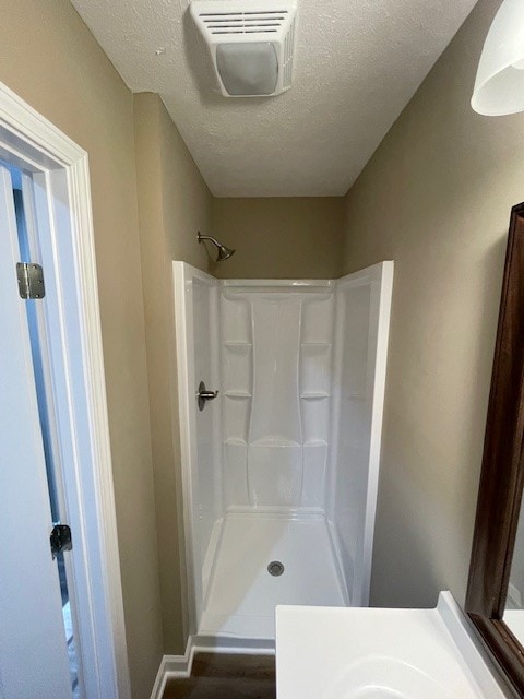 bathroom with a shower, vanity, wood-type flooring, and a textured ceiling