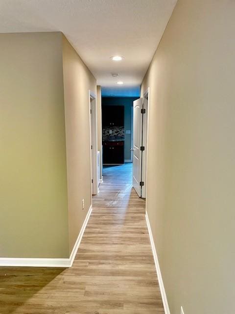 corridor featuring light wood-style flooring, recessed lighting, and baseboards