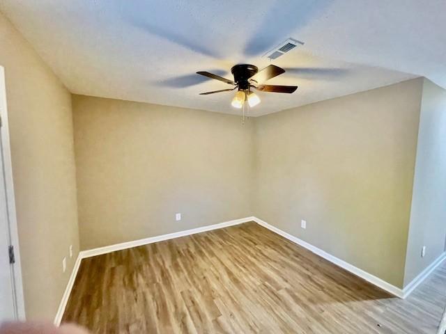 unfurnished room featuring visible vents, baseboards, a ceiling fan, and wood finished floors
