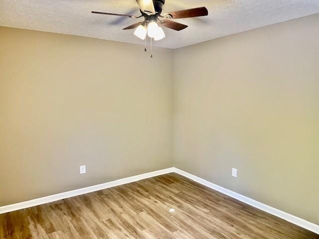 unfurnished room with baseboards, ceiling fan, wood finished floors, and a textured ceiling