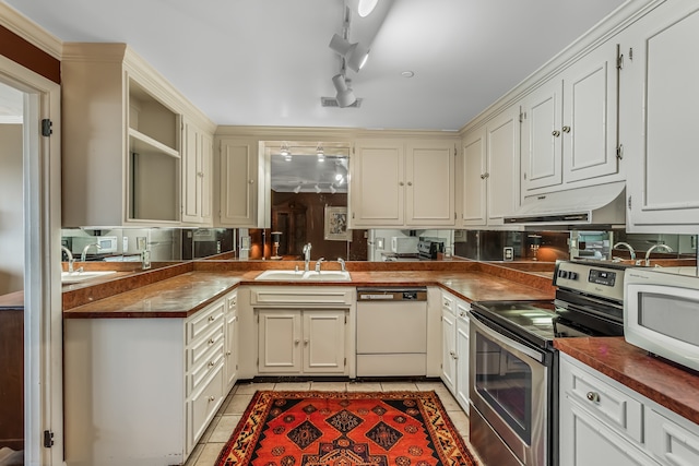 kitchen featuring white appliances, butcher block countertops, light tile patterned floors, track lighting, and sink