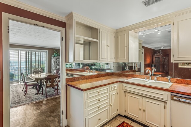 kitchen with cream cabinets, white dishwasher, sink, and light parquet flooring