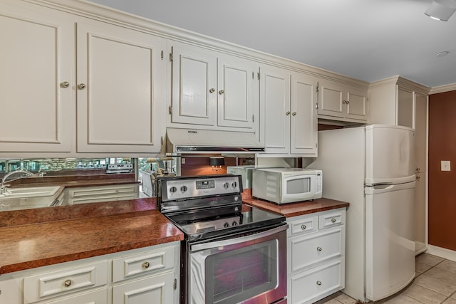 kitchen with white appliances, white cabinetry, light tile patterned floors, and sink