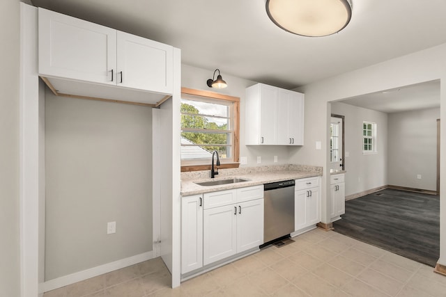 kitchen featuring white cabinetry, stainless steel dishwasher, sink, and light hardwood / wood-style flooring