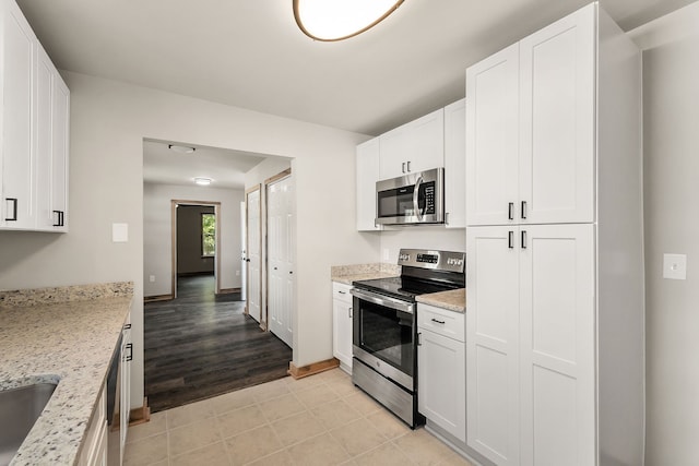 kitchen with white cabinetry, stainless steel appliances, light hardwood / wood-style floors, and light stone counters