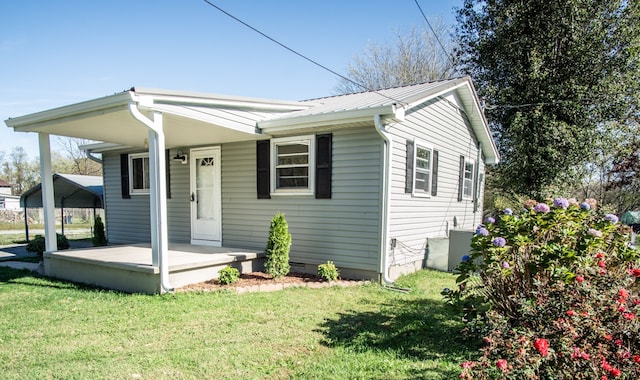 view of front of property with central AC unit, covered porch, a front yard, and a carport