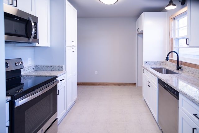 kitchen with white cabinetry, appliances with stainless steel finishes, sink, and light stone counters