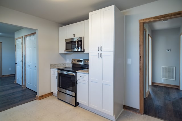 kitchen featuring white cabinets, light stone countertops, stainless steel appliances, and light hardwood / wood-style flooring