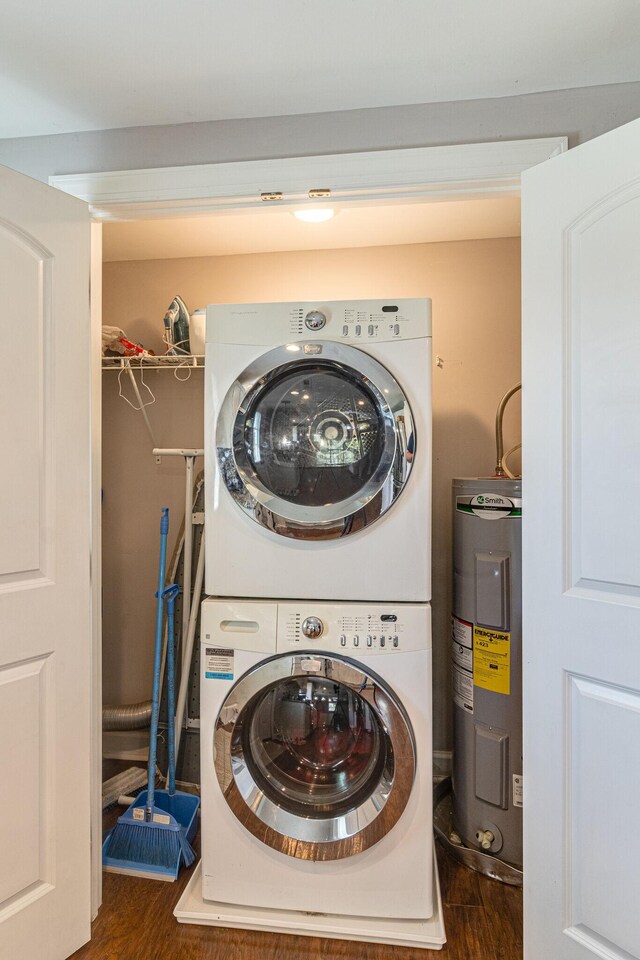 washroom featuring stacked washer and dryer, electric water heater, and dark hardwood / wood-style floors