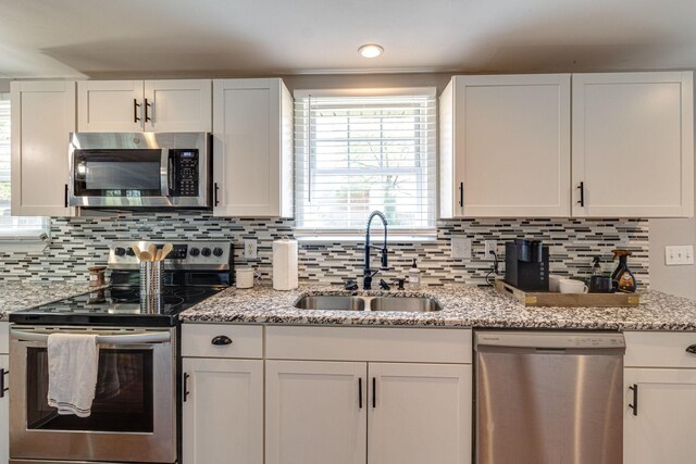 kitchen with appliances with stainless steel finishes, backsplash, white cabinetry, and sink