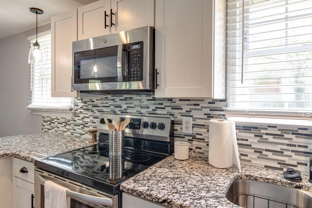 kitchen with white cabinetry, appliances with stainless steel finishes, light stone counters, and tasteful backsplash