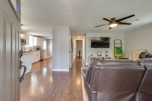 living room with dark hardwood / wood-style flooring, ceiling fan, and sink