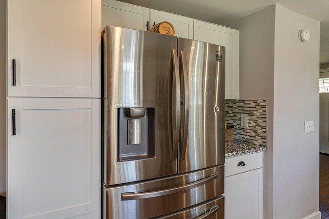 kitchen with dark stone countertops, stainless steel refrigerator with ice dispenser, backsplash, and white cabinetry