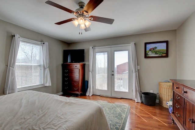 bedroom featuring multiple windows, light wood-type flooring, ceiling fan, and french doors