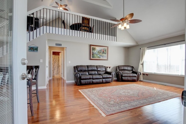 living room with ceiling fan, light hardwood / wood-style flooring, and high vaulted ceiling