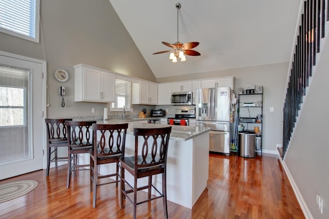 kitchen featuring stainless steel appliances, plenty of natural light, high vaulted ceiling, and white cabinetry