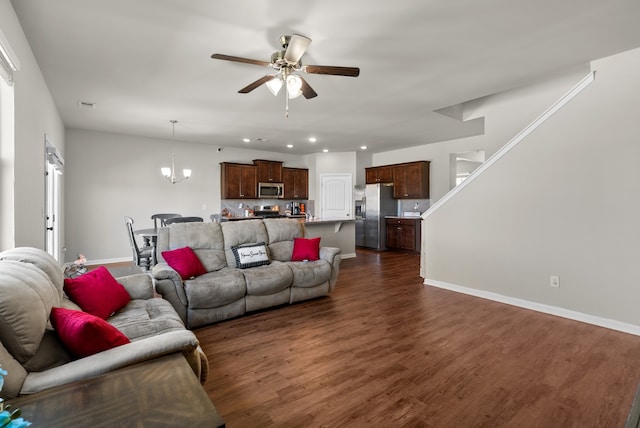 living room with ceiling fan with notable chandelier and dark wood-type flooring