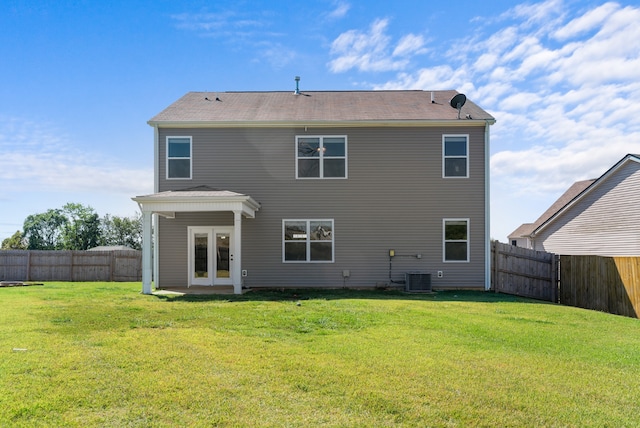 rear view of house with central air condition unit and a yard