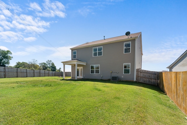 back of property with a lawn and central AC