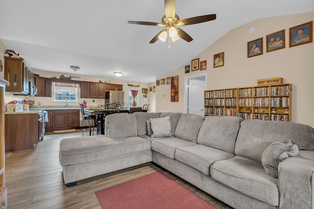 living room with light hardwood / wood-style floors, vaulted ceiling, and ceiling fan