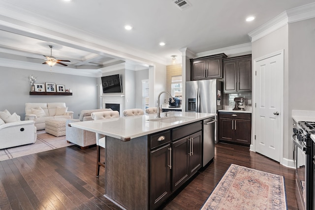 kitchen featuring an island with sink, sink, dark wood-type flooring, a kitchen breakfast bar, and stainless steel appliances