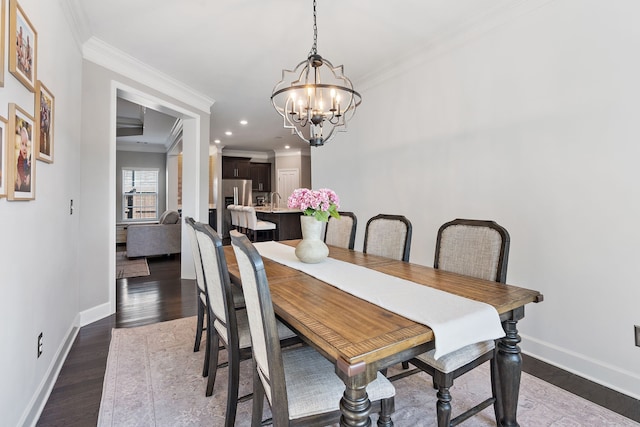 dining space featuring ornamental molding, a notable chandelier, sink, and dark hardwood / wood-style flooring