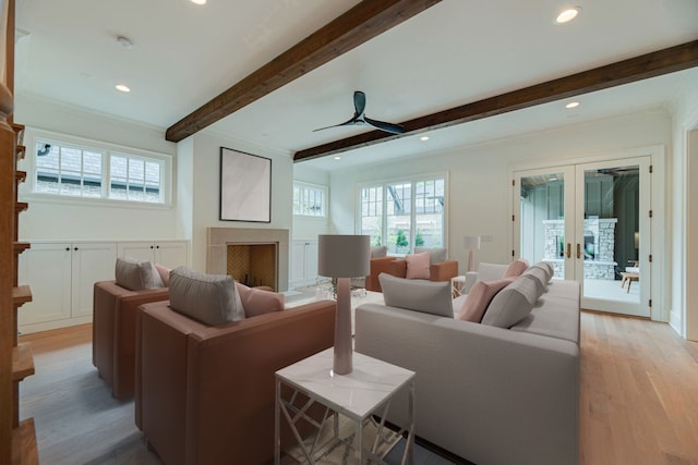 living room with ceiling fan, light wood-type flooring, ornamental molding, beamed ceiling, and french doors