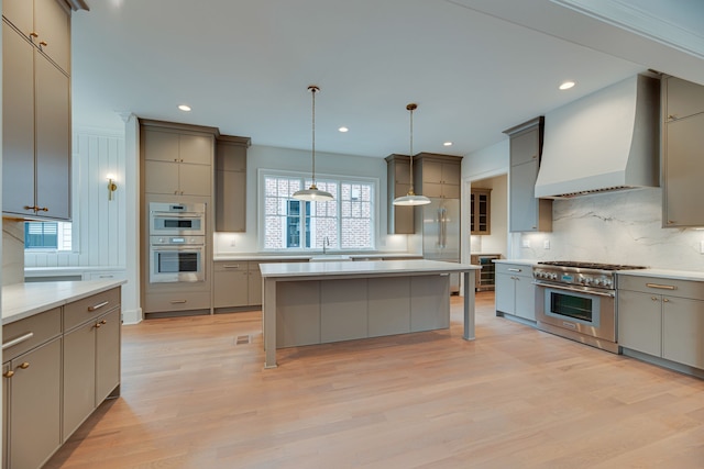 kitchen featuring a kitchen island, a breakfast bar area, hanging light fixtures, custom range hood, and stainless steel appliances