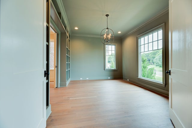 spare room with an inviting chandelier, ornamental molding, and light hardwood / wood-style floors