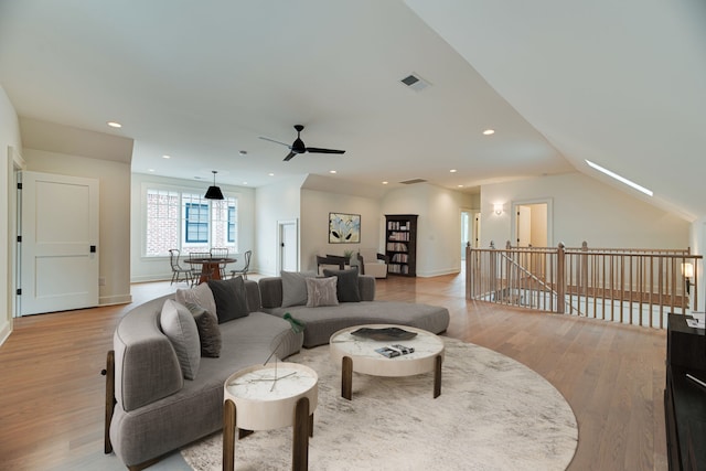 living room with ceiling fan, light wood-type flooring, and vaulted ceiling