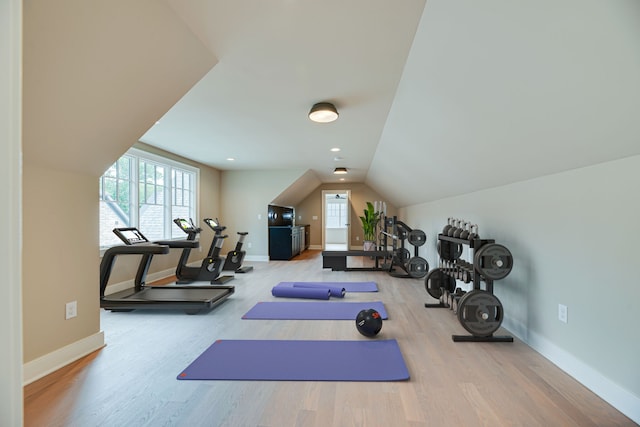 exercise room with lofted ceiling and light hardwood / wood-style flooring