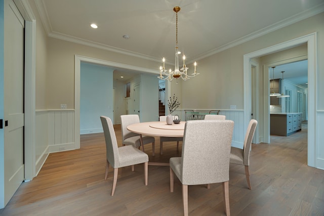 dining room featuring crown molding, an inviting chandelier, and light wood-type flooring