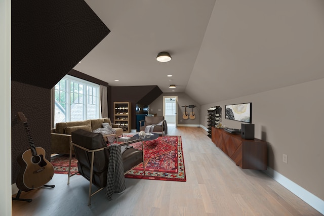 living room with vaulted ceiling, a healthy amount of sunlight, and light hardwood / wood-style floors