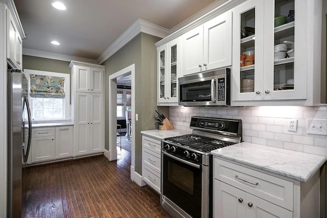 kitchen featuring ornamental molding, white cabinets, stainless steel appliances, dark hardwood / wood-style flooring, and light stone countertops