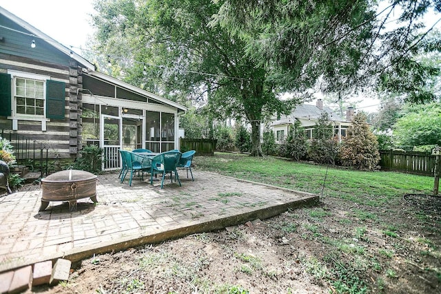 view of yard with a fire pit, a sunroom, and a patio