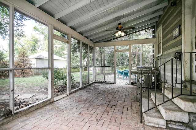 unfurnished sunroom featuring vaulted ceiling with beams and ceiling fan