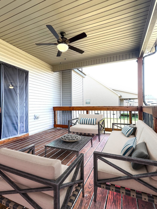 deck featuring ceiling fan and an outdoor living space with a fire pit