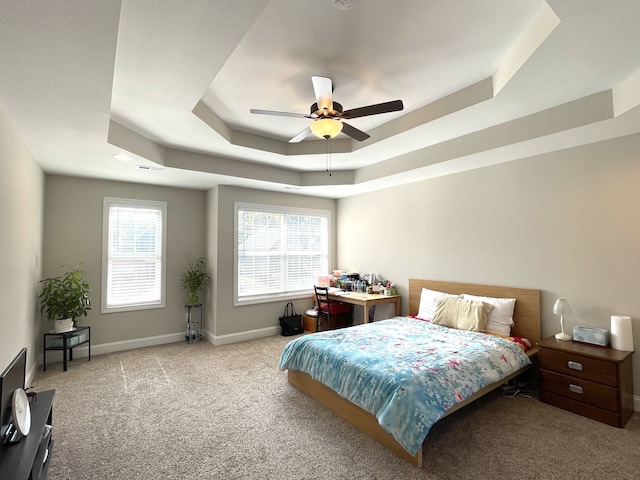 bedroom featuring ceiling fan, light colored carpet, and a raised ceiling