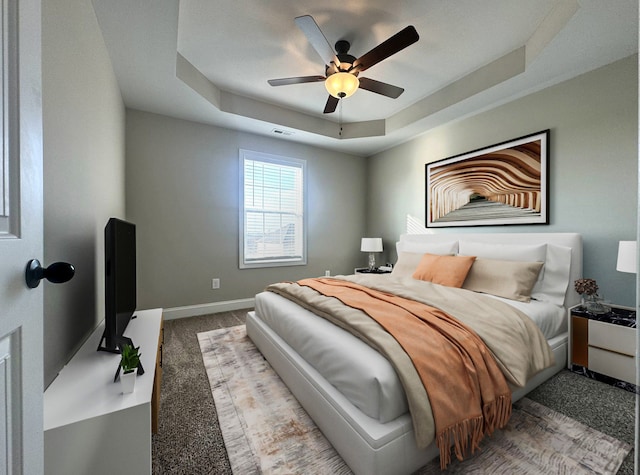 bedroom with carpet floors, a raised ceiling, and ceiling fan