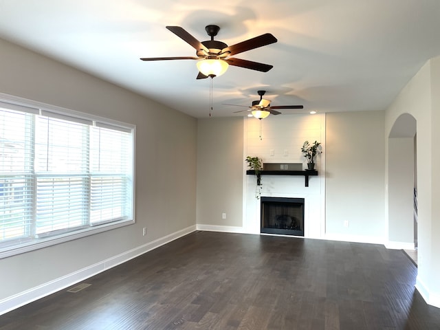 unfurnished living room featuring ceiling fan and dark wood-type flooring