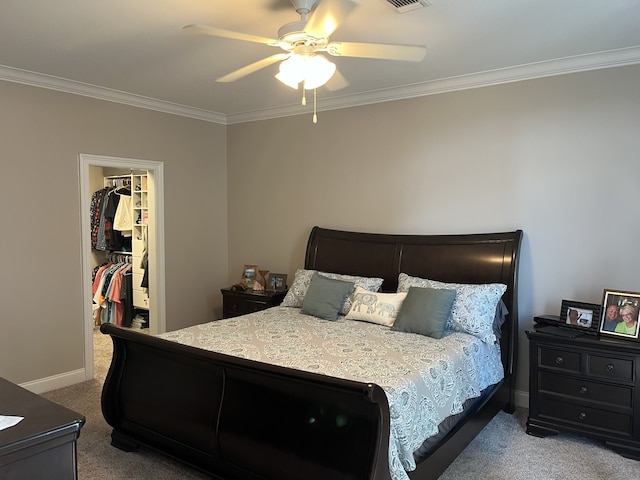 bedroom with a spacious closet, ceiling fan, carpet flooring, and crown molding