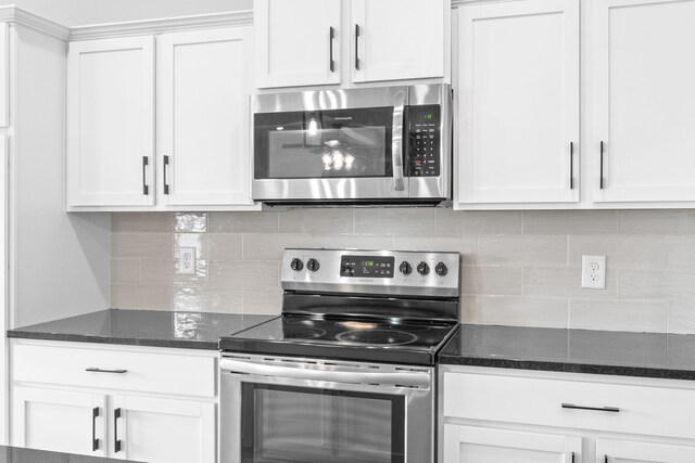 kitchen featuring dark stone counters, stainless steel appliances, white cabinets, and tasteful backsplash